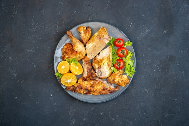 Top view fried chicken tomatoes lemon slices in oval plate on table free space