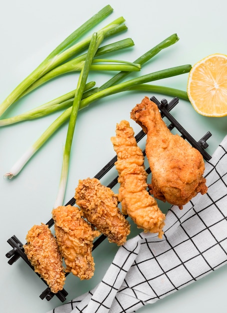 Top view fried chicken on tray with green onions, lemon and kitchen towel