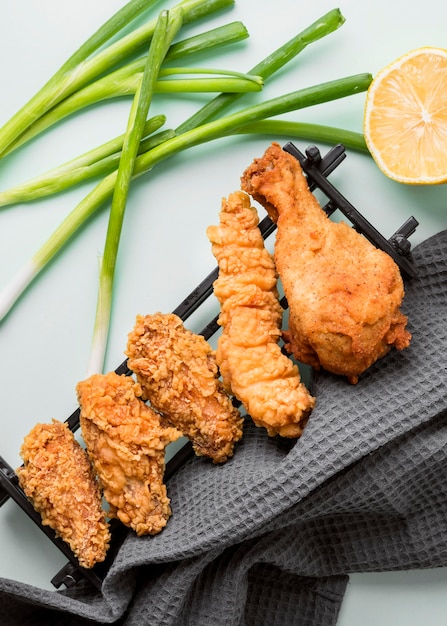 Vista dall'alto pollo fritto sul vassoio con cipolle verdi e limone