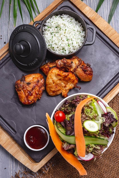 Top view fried chicken with rice in a pan with sauce and vegetable salad