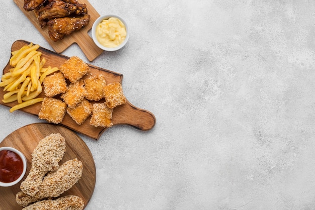 Top view of fried chicken with sauces and nuggets on chopping boards with copy space