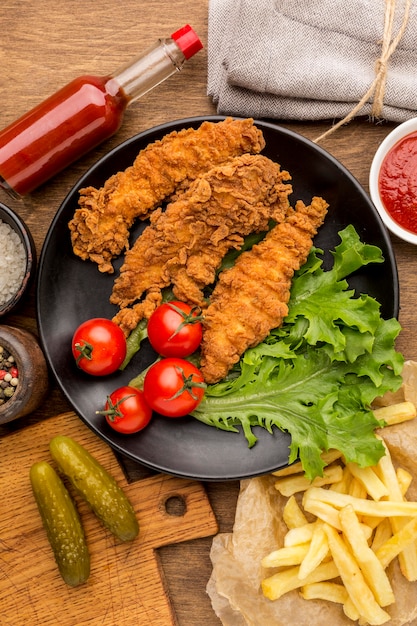 Top view fried chicken with tomatoes and salad on plate with fries