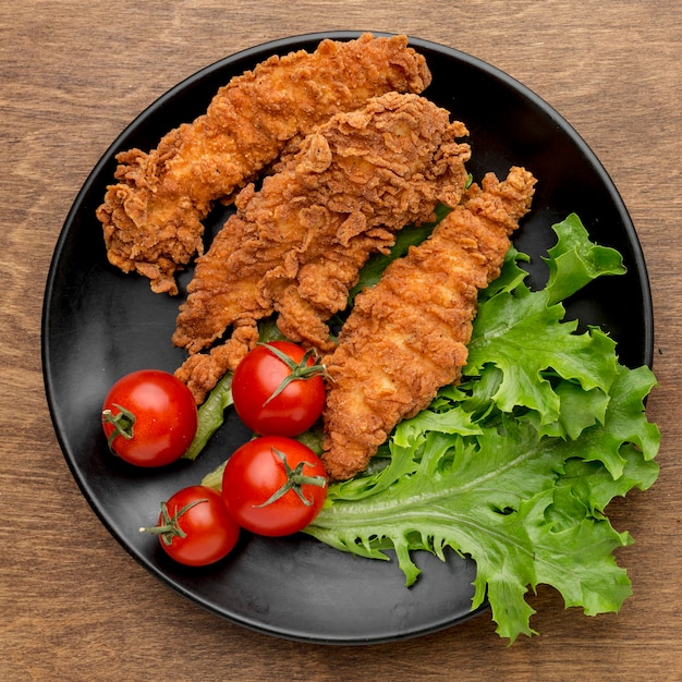 Foto gratuita vista dall'alto pollo fritto con pomodori e insalata sulla piastra