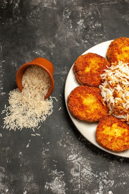 Vista dall'alto cotolette fritte con riso cotto su carne di foto piatto superficie grigio scuro