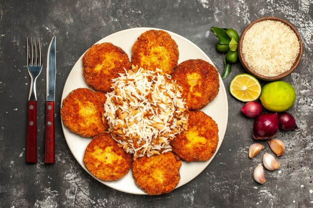 Top view fried cutlets with cooked rice on the dark surface food dish meat rissole