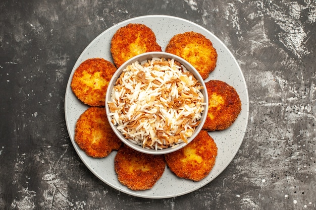 Vista dall'alto cotolette fritte con riso cotto su una polpetta di carne di cibo superficie scura