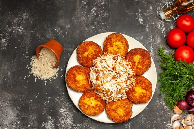 Top view fried cutlets with cooked rice and greens on grey desk dish photo meat