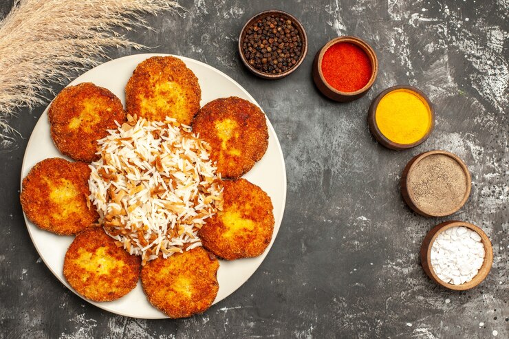 मुफ़्त फोटो ऊपरी दृश्य तले हुए कटलेट का, गहरे फर्श फ़ूड मीट डिश पर पके हुए चावल और मसालों के साथ