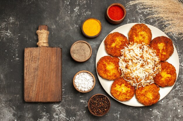 Top view fried cutlets with cooked rice and seasonings on a dark surface dish photo meat