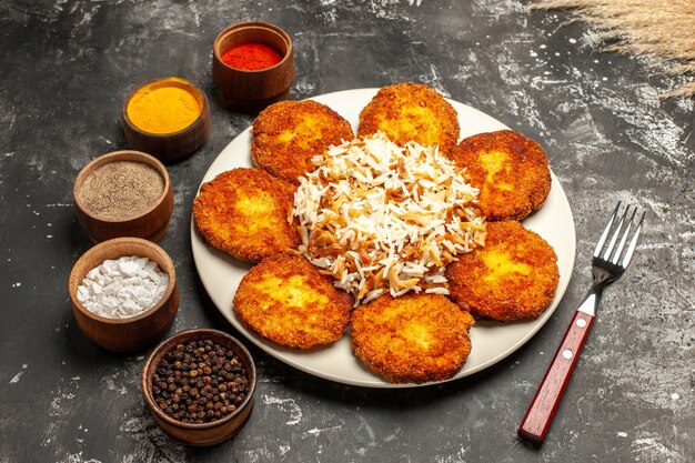 Foto gratuita vista dall'alto cotolette fritte con riso cotto e condimenti sulla carne della foto del piatto di cibo di superficie scura