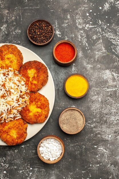 Top view fried cutlets with cooked rice and seasonings on dark surface food dish photo