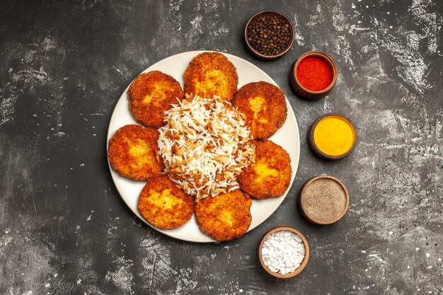 Top view fried cutlets with cooked rice and seasonings on dark surface food photo meat