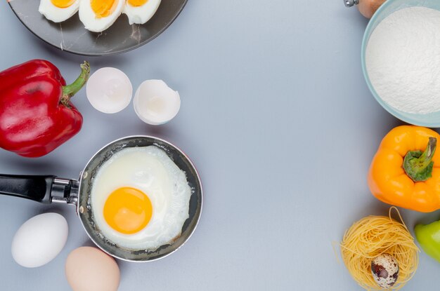 Вид сверху жареного яйца на сковороде с яичной скорлупой на сером фоне с копией пространства