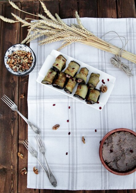 Top view of fried eggplant rolls with cream cheese walnuts and garlic on a plate on wooden table