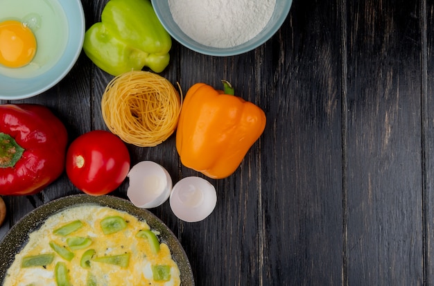 Top view of fried eggs with egg shells with colorful bell peppers on a wooden background with copy space