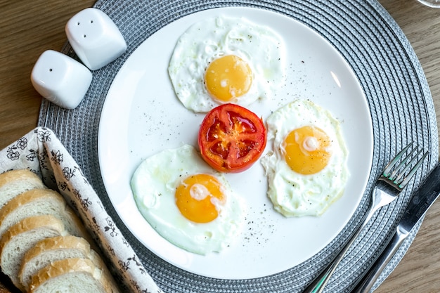 Бесплатное фото Вид сверху яичница с помидорами на тарелку с солью и перцем на столе