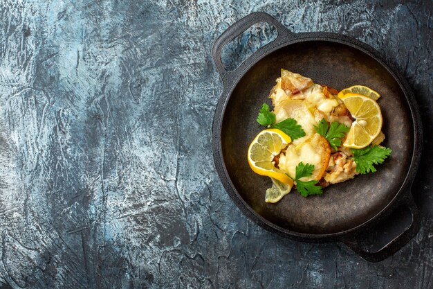 灰色の背景にレモンとパセリと鍋で揚げ魚の上面図