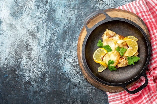 Top view fried fish in pan on wood board red and white checkered tablecloth on grey background