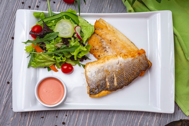 Вид сверху жареная рыба с овощным салатом и соусом