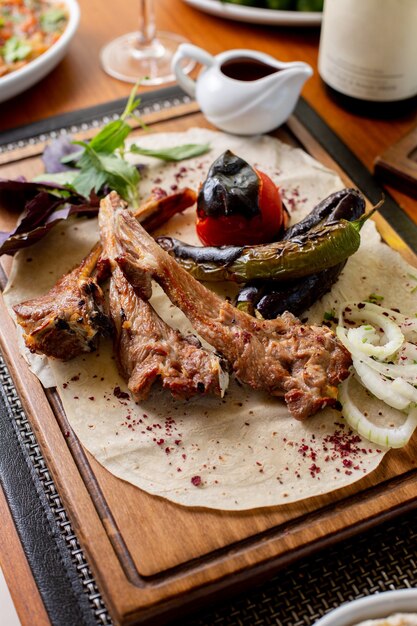Вид сверху жареные мясные кости с жареными овощами и соусом на столе еда обед ужин ресторан