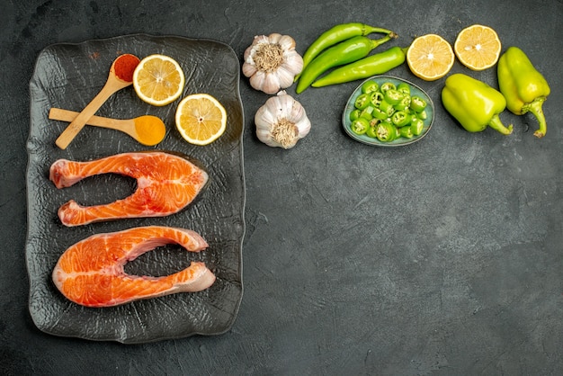 Top view fried meat slices with peppers garlic and lemon on dark background