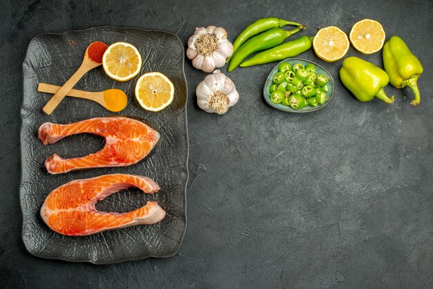 Top view fried meat slices with peppers garlic and lemon on dark background