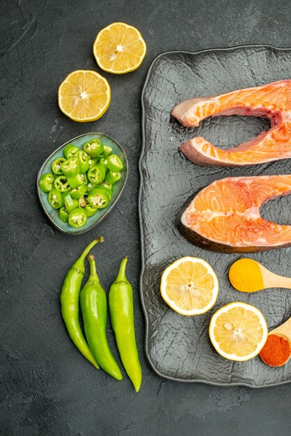 Top view fried meat slices with peppers and lemon on a dark background