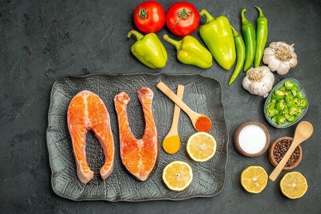 Top view fried meat slices with seasonings and fresh vegetables on dark background