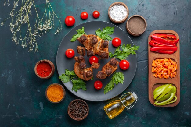 Top view fried meat slices with vegetables and seasonings on dark-blue desk vegetables meal food meat dinner health
