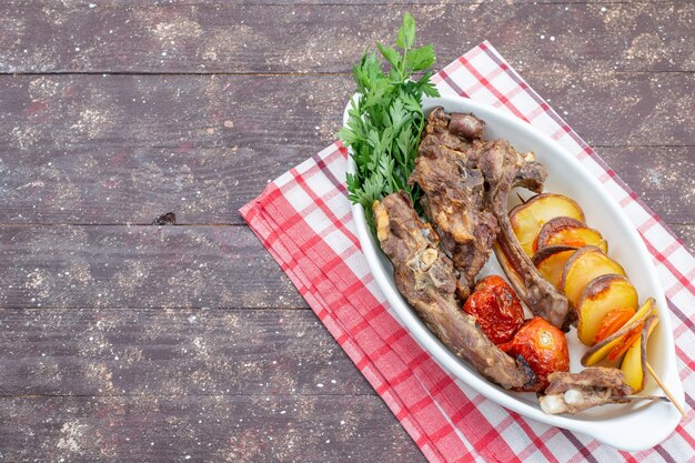 Вид сверху жареного мяса с зеленью и запеченными сливами внутри тарелки на коричневом деревянном столе, еда, мясное блюдо, ужин, овощ