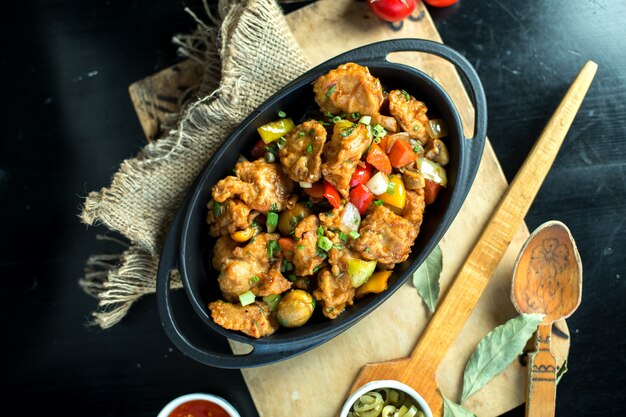 Top view fried meat with vegetables in a pan on the board