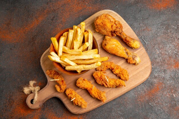 Top view of fried potato and chicken on wooden cutting board