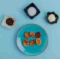 Free photo top view of fried potato slices in plate with black pepper salt and mayonnaise on blue surface