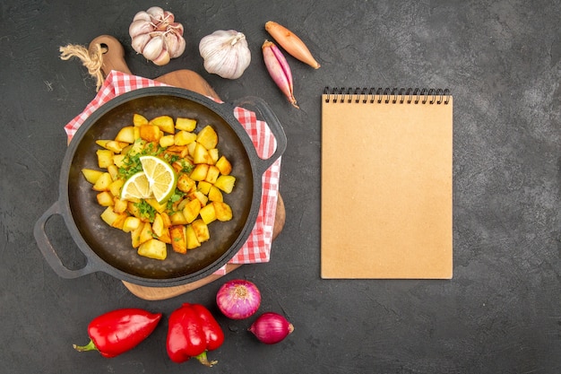 Top view fried potatoes inside pan with vegetables on dark background