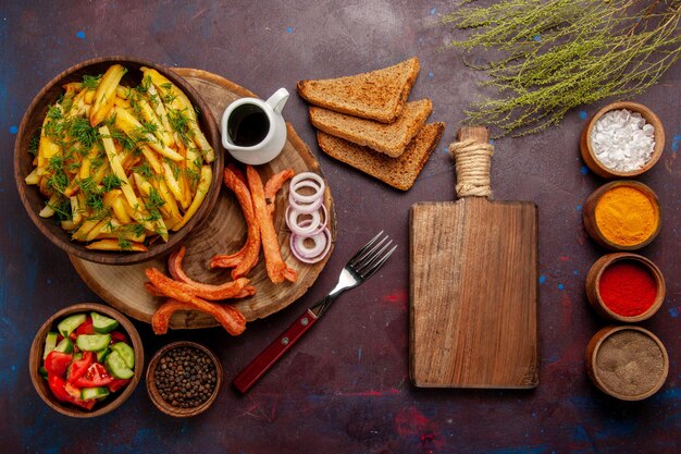 Top view fried potatoes with seasonings bread loafs and different vegetables on dark surface