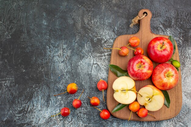 Top view from afar apples the appetizing red apples cherries on the cutting board