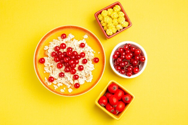 Вид сверху на ягоды, тарелки с ягодами, аппетитные желтые конфеты, овсяные хлопья