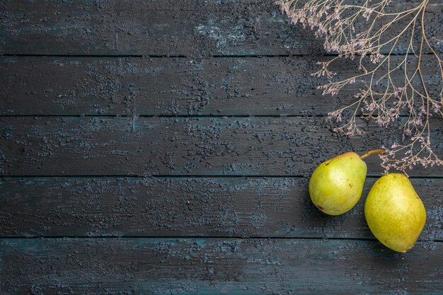 遠くの枝と梨からの上面図テーブルの右側にある木の枝の横にある2つの熟した梨