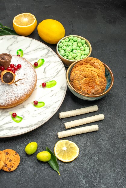 Top view from afar a cake a cake with berries jam citrus fruits with leaves sweets cookies