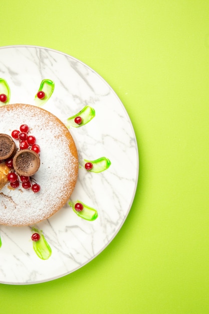 Vista dall'alto da lontano una torta una torta con cialde ribes rosso zucchero a velo sul piatto