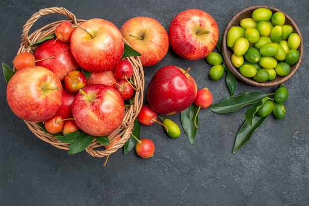 Top view from afar citrus fruits mandarins apples cherries bowl of citrus fruits with leaves