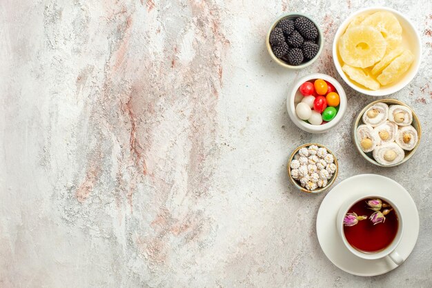 Top view from afar cup of tea a cup of black tea and bowls of appetizing sweets on the table