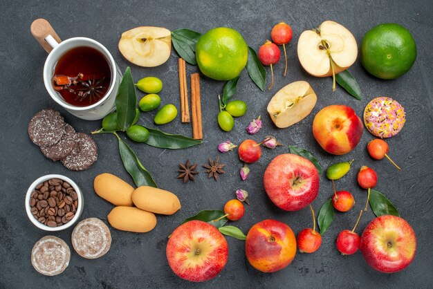 Top view from afar a cup of tea a cup of herbal tea cinnamon sticks sweets fruits and berries