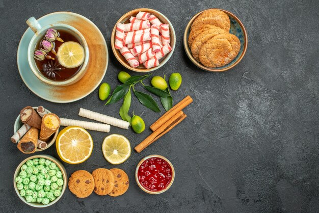 Top view from afar a cup of tea a cup of herbal tea with lemon cookies candies waffles cinnamon