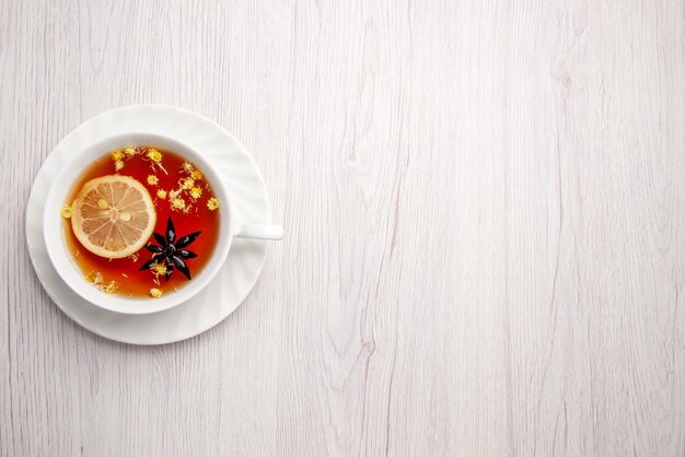 Top view from afar a cup of tea on the saucer a cup of tea with lemon on the saucer on the left side of the wooden table