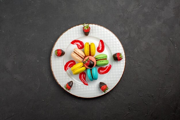 Top view from afar French macaroon French macaroon with chocolate-covered strawberries in the center of the dark table