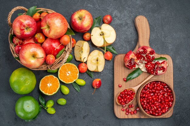 Top view from afar fruits different fruits next to the board with seeds of pomegranate