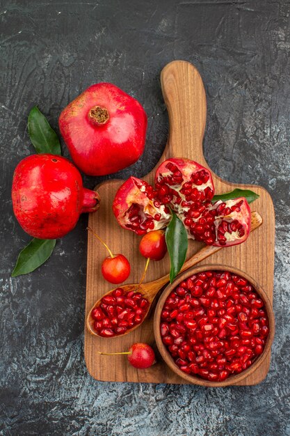 Top view from afar fruits pomegranate seeds spoon cherries pomegranate on the board