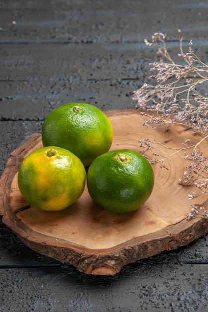 Free photo top view from afar lime on board limes on brown board on the grey table next to branches