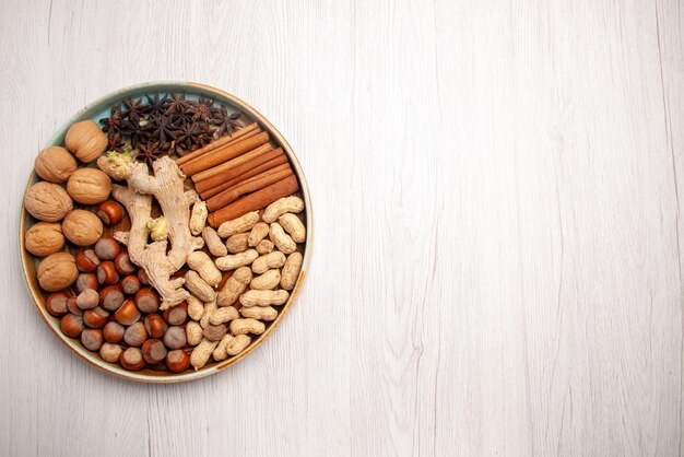 Top view from afar nuts and cinnamon walnuts hazelnuts cinnamon sticks peanuts and star anise on the left side of the table